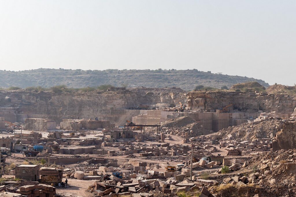 industrial mining operations in large rock quarry under bright daylight in Aravalli range